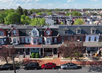 Historic row houses with distinct architectural details, tree-lined streets, and parked cars. Aerial truck shot in American city during spring.